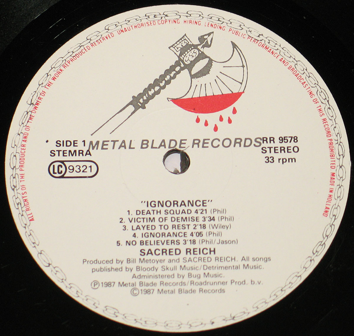 Sacred Reich Ignorance 1987 vinyl record label, Side 1. The Metal Blade Records label features a black-and-white battle axe logo dripping with blood. The album title 'Ignorance' is printed in bold capital letters, followed by track listings including 'Death Squad,' 'Victim of Demise,' and 'Ignorance.' Production credits, copyright information, and the catalog number RR 9578 are also displayed.
